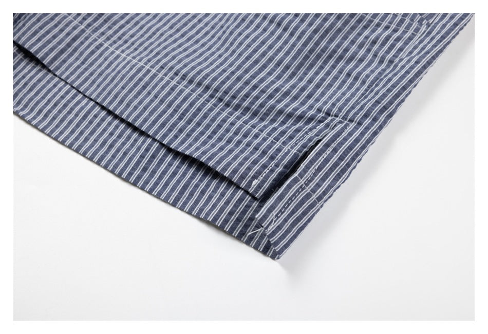 Close-up of a folded, stitched edge and seam on the blue-gray striped shirt.
