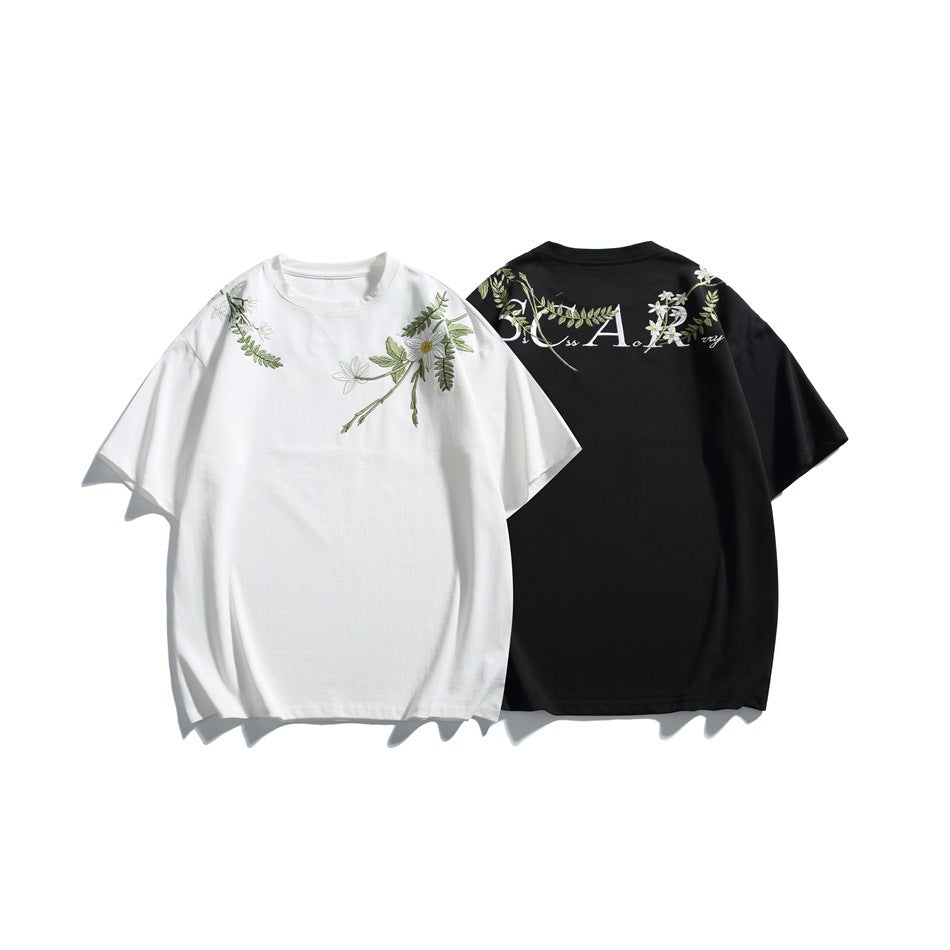 White front-view and black back-view short-sleeve T-shirts with floral embroidery and lettering.