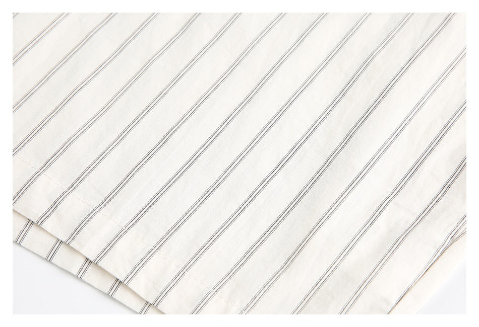 Close-up of the cream shirt's thin dark stripes and stitched hem.
