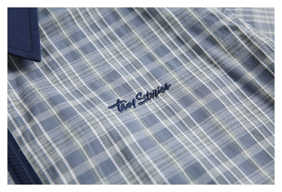 Close-up of blue-gray plaid fabric with small navy cursive embroidery.