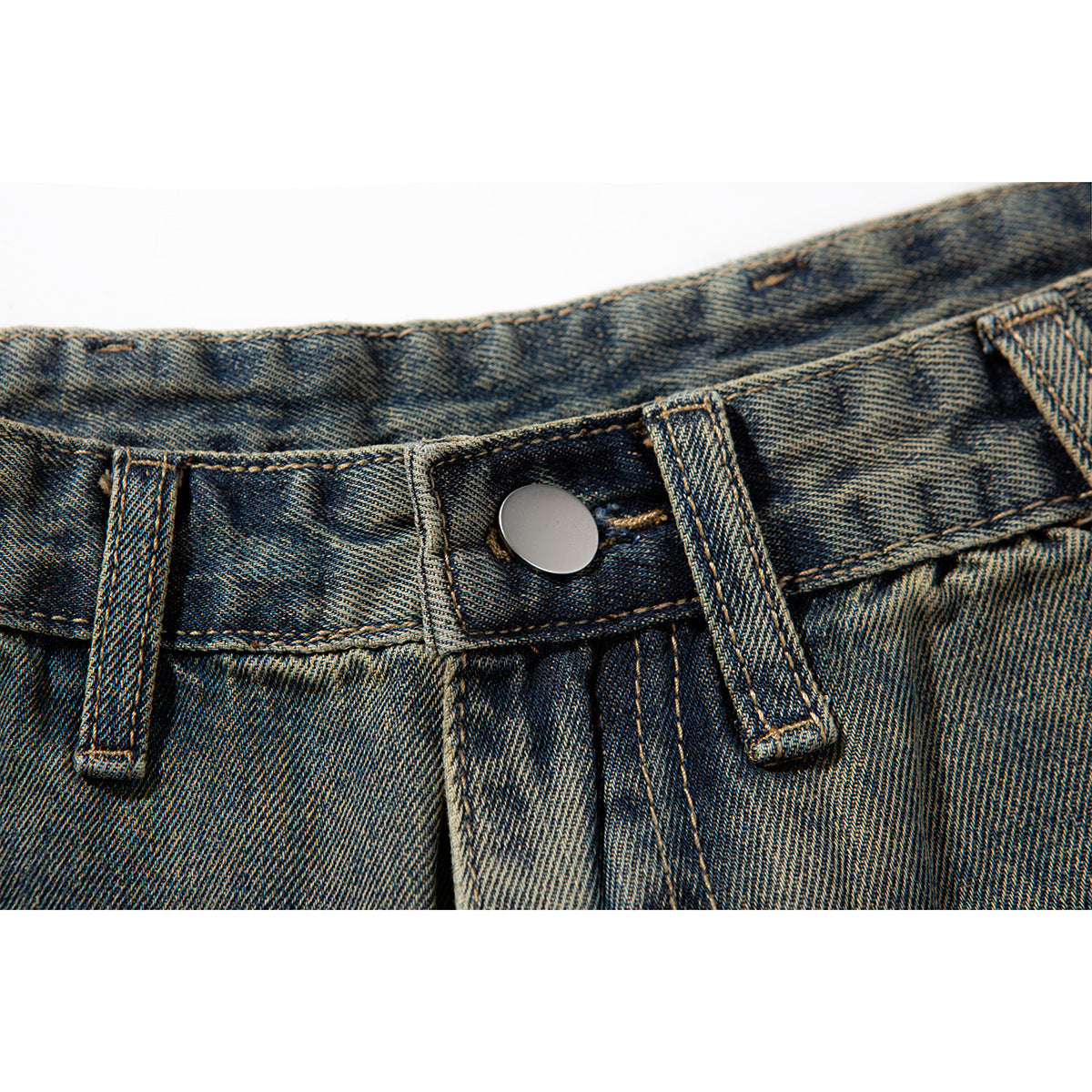 Close-up of the metal button, belt loops, and fly on blue-brown washed denim shorts.