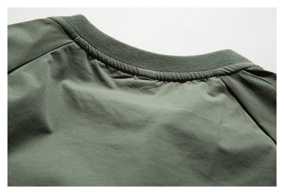 Close-up of a ribbed crew neckline and shoulder seams on a dark olive-green garment.