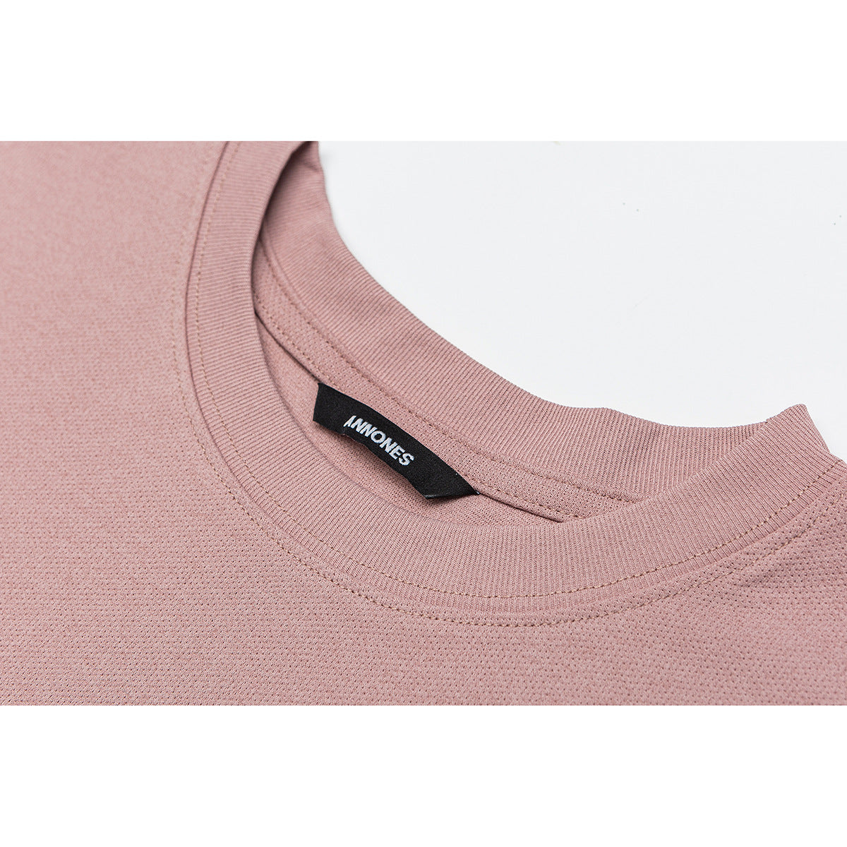 Close-up of a dusty pink crew-neck T-shirt collar, stitching, and black inner label.