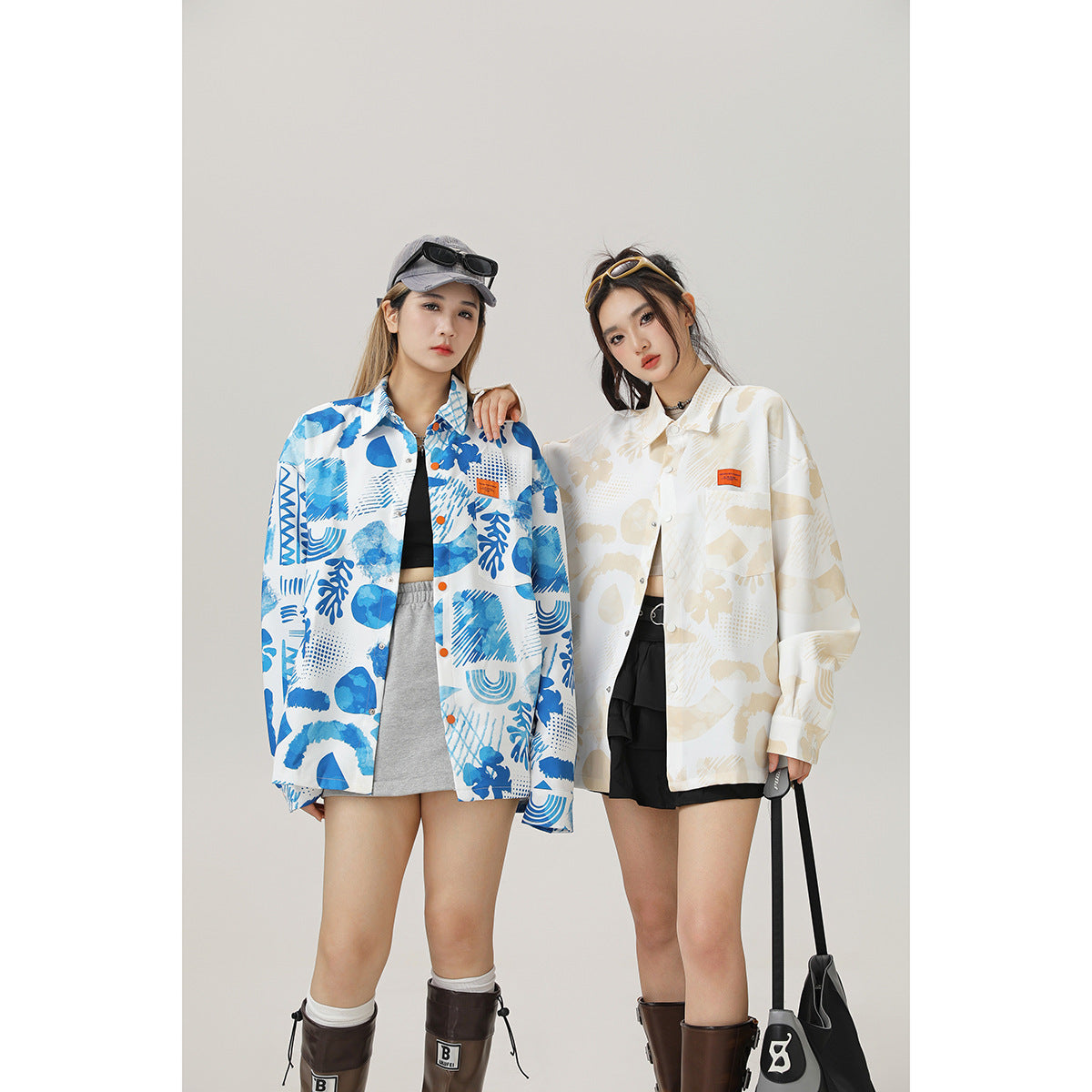 Two models wearing oversized patterned button-up shirts in blue and white or cream and beige, shown from the front.