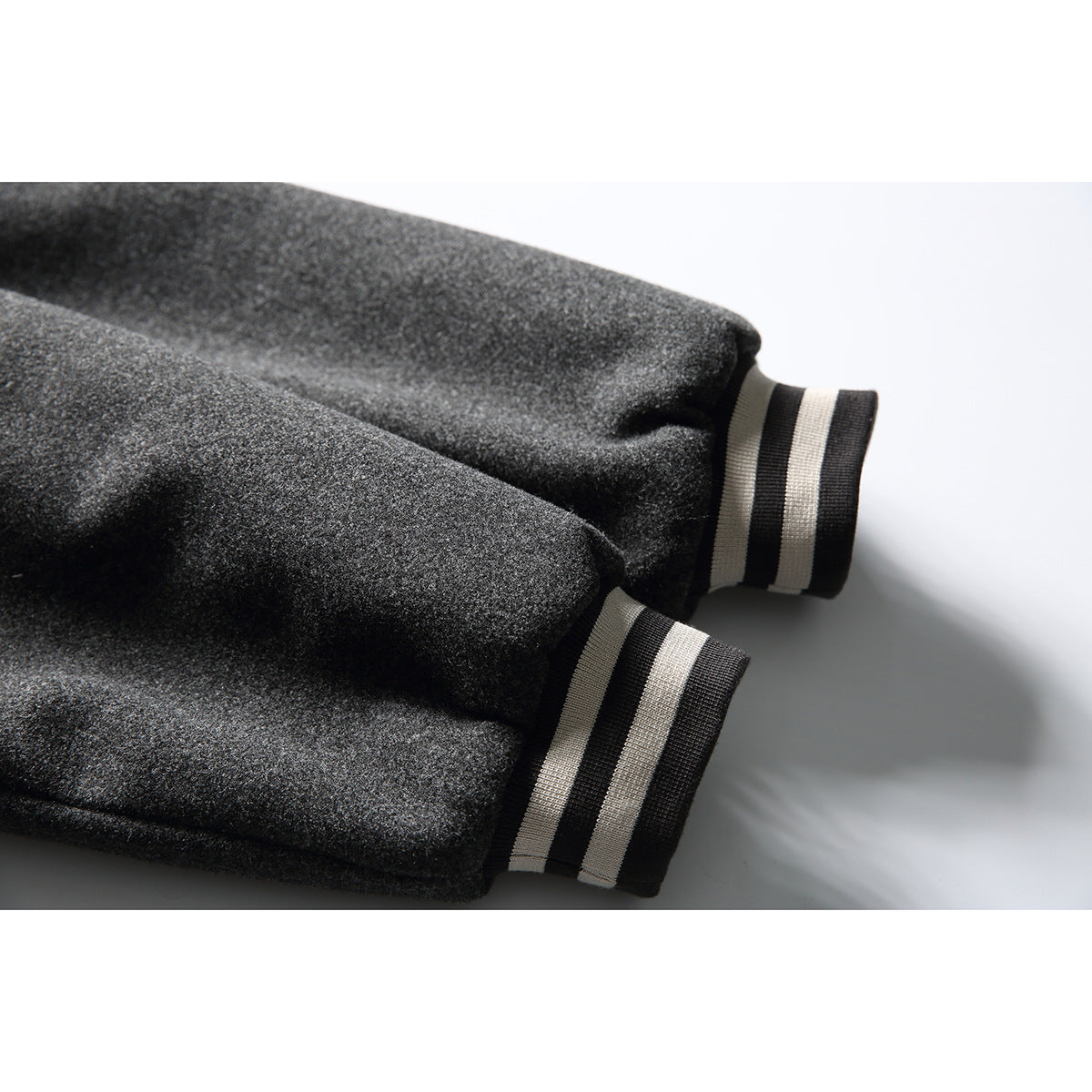 Close-up of charcoal gray jacket sleeves with black-and-cream striped ribbed cuffs.