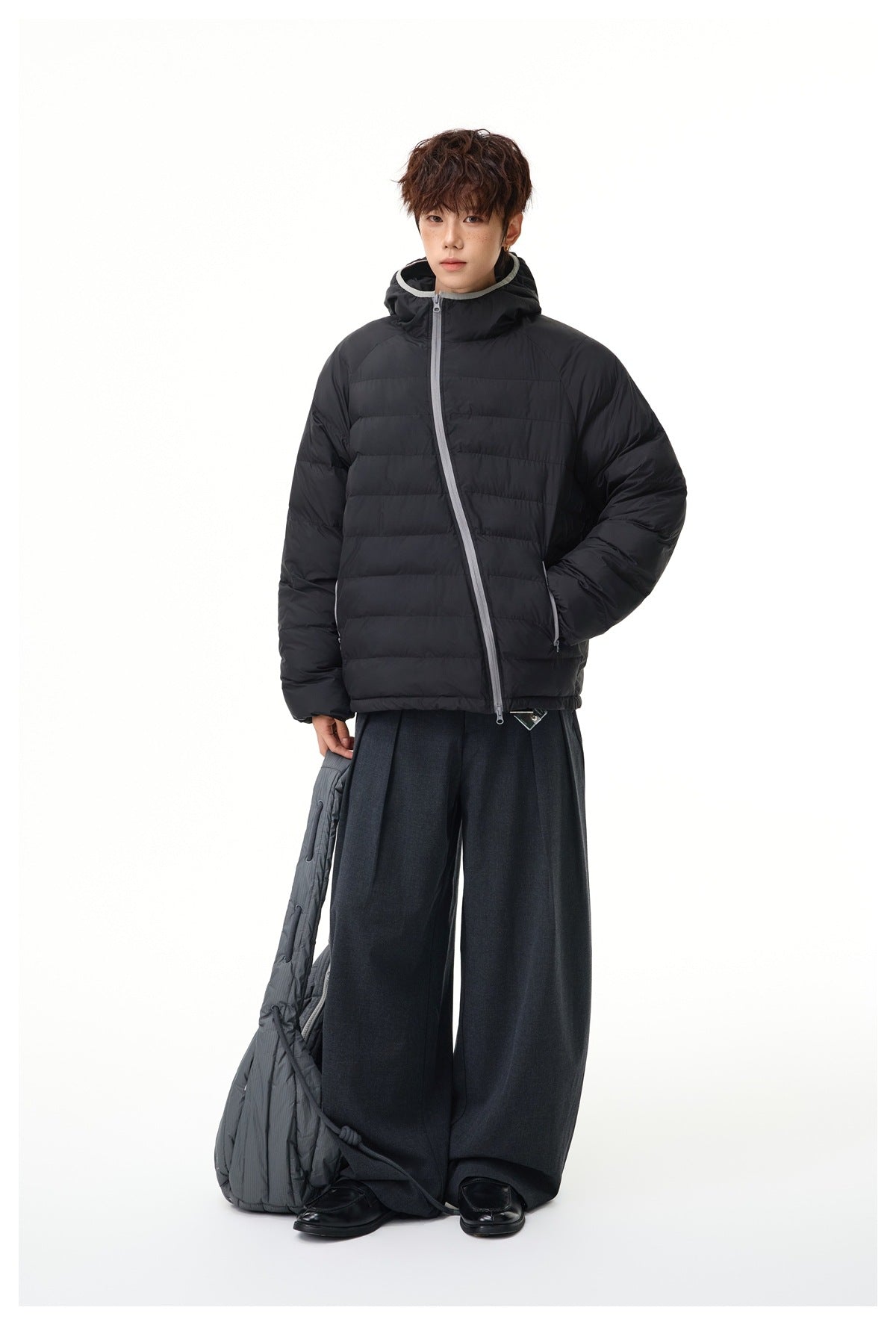 Full-length model wearing a black hooded quilted puffer jacket with gray trim and dark wide-leg trousers.