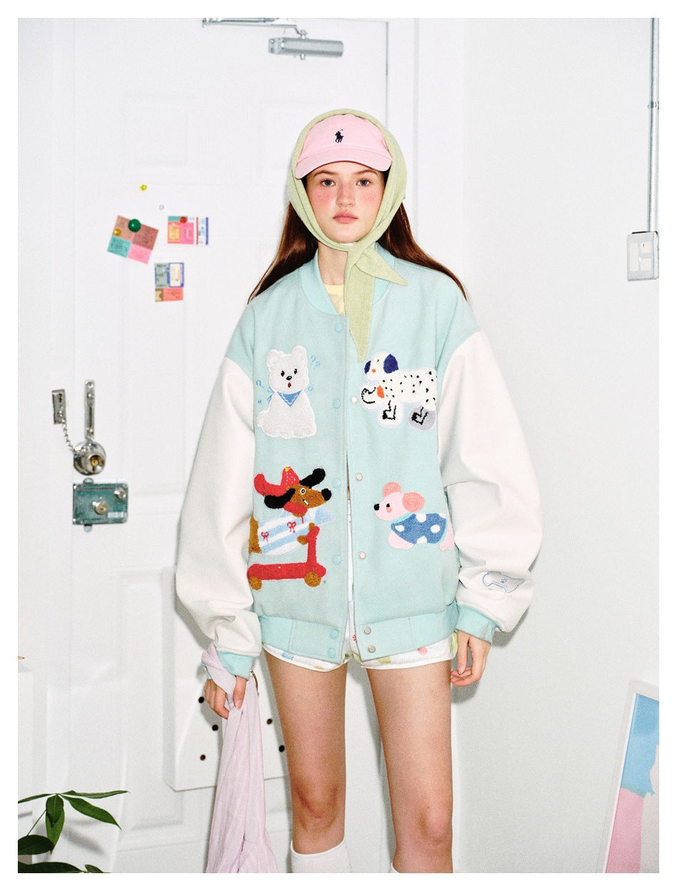Model wearing mint green varsity jacket with white sleeves and animal patches, with a pink cap and green headscarf