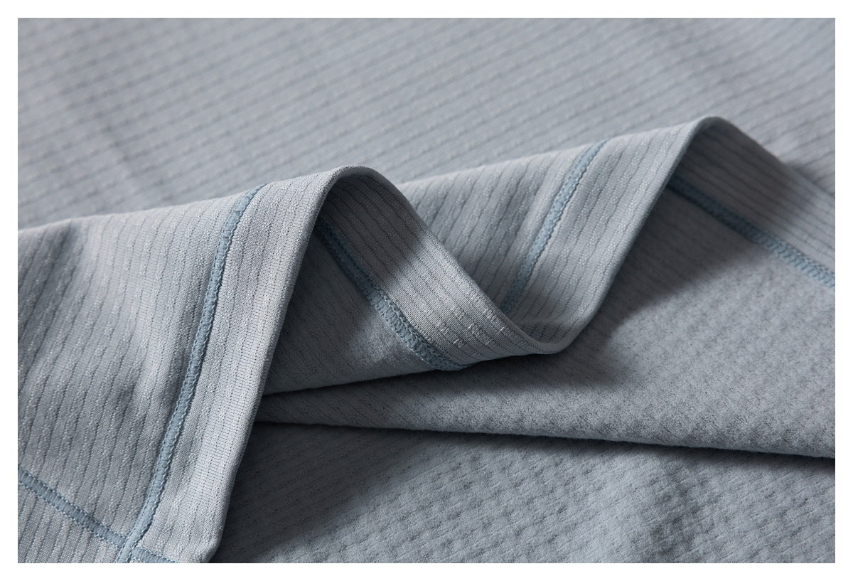 Close-up of folded gray-blue shirt fabric showing the textured surface, seams, and inner side.