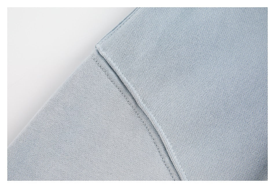 Close-up of a pale blue sweatshirt shoulder seam and smooth fabric.