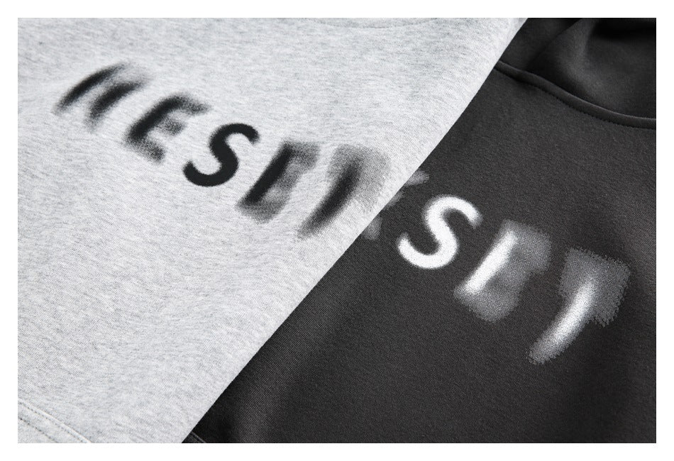 Close-up of blurred contrasting lettering printed on light gray and dark hoodie fabric.