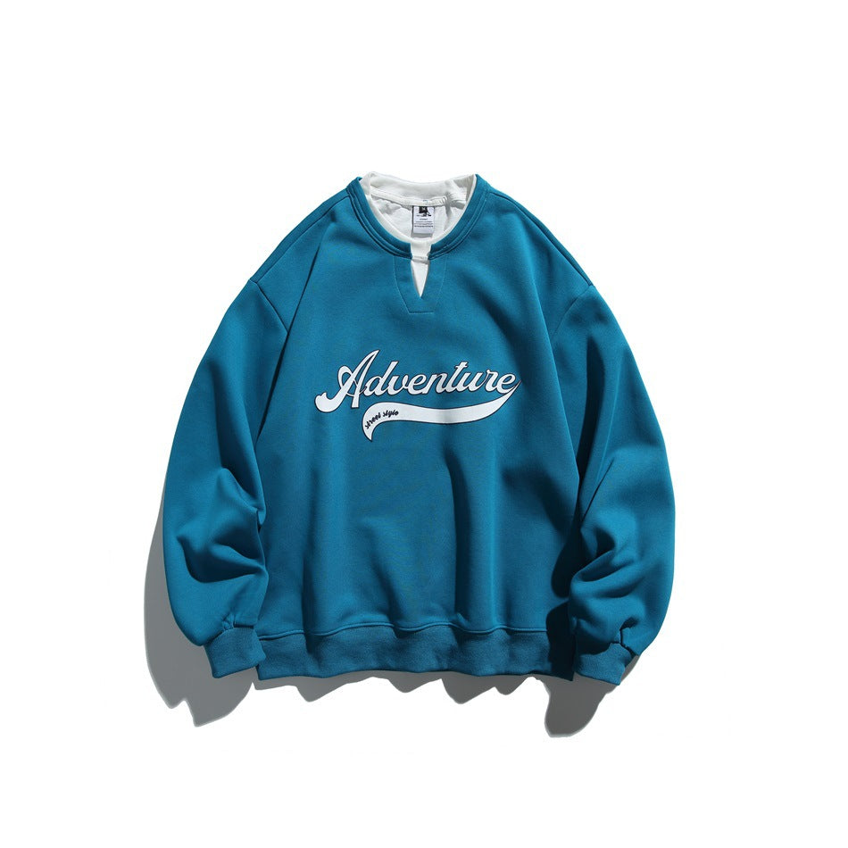 Blue crewneck sweatshirt with V-notch, white under-collar and white script Adventure graphic, flat lay