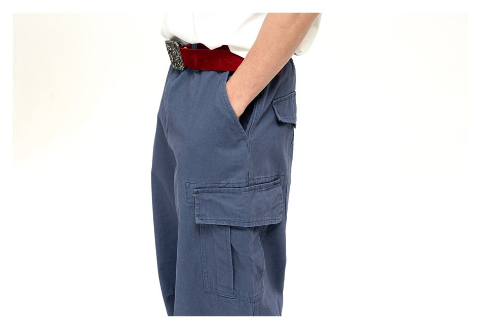 Side view of a person wearing slate-blue wide-leg cargo pants with a large flap pocket and a red belt.