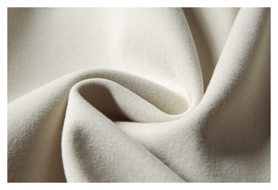 Close-up of pale cream fabric arranged in folds, showing its surface texture.