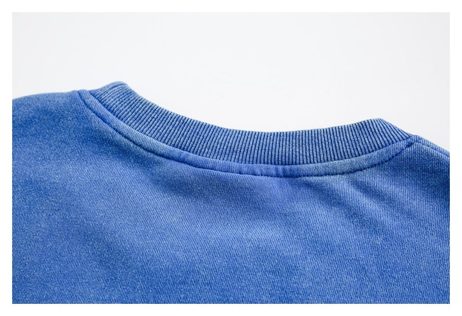 Close-up of a blue sweatshirt's ribbed crew neckline and stitching.