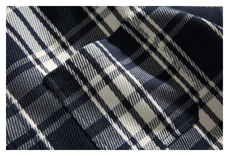 Close-up showing the navy and cream plaid fabric and chest pocket stitching.