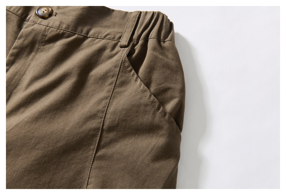 Close-up of brown trousers showing an angled side pocket and gathered elastic waistband.