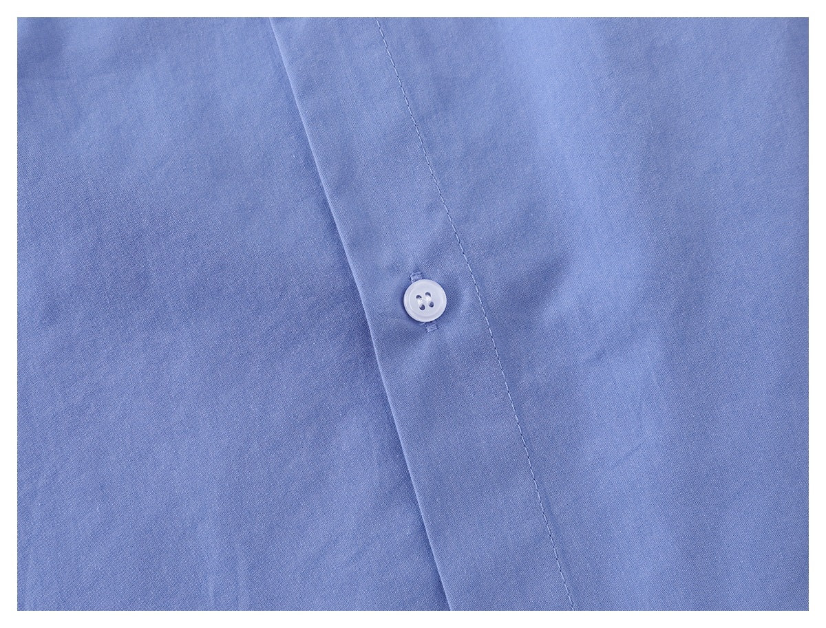 Close-up of a white button on the placket of a light blue shirt.