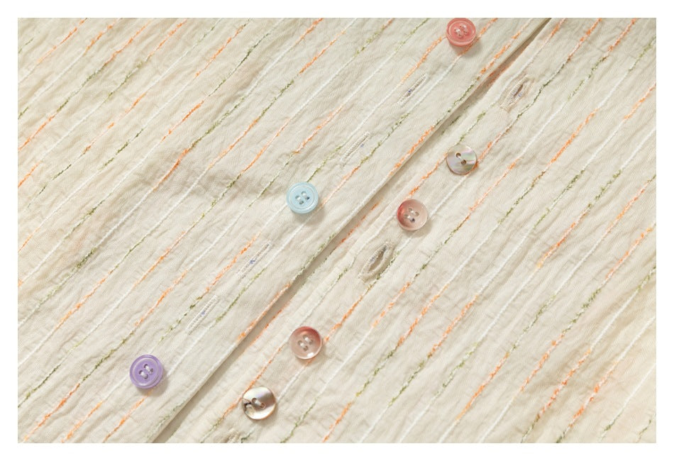 Close-up of the button placket on an ivory shirt with raised orange and olive stripes and colorful buttons.