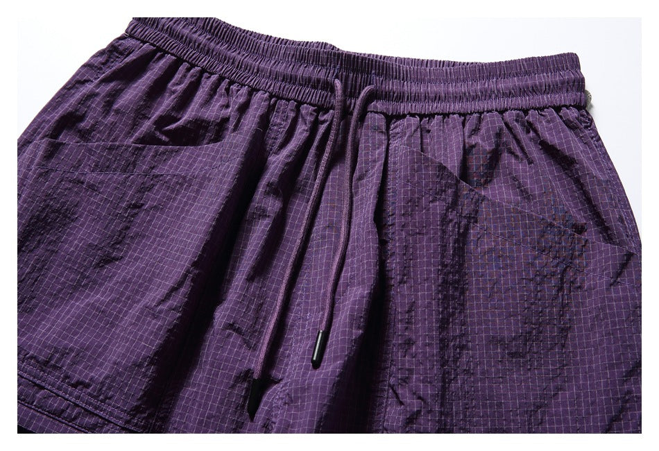 Close-up of the purple shorts' elastic drawstring waistband, grid pattern and upper cargo pockets.