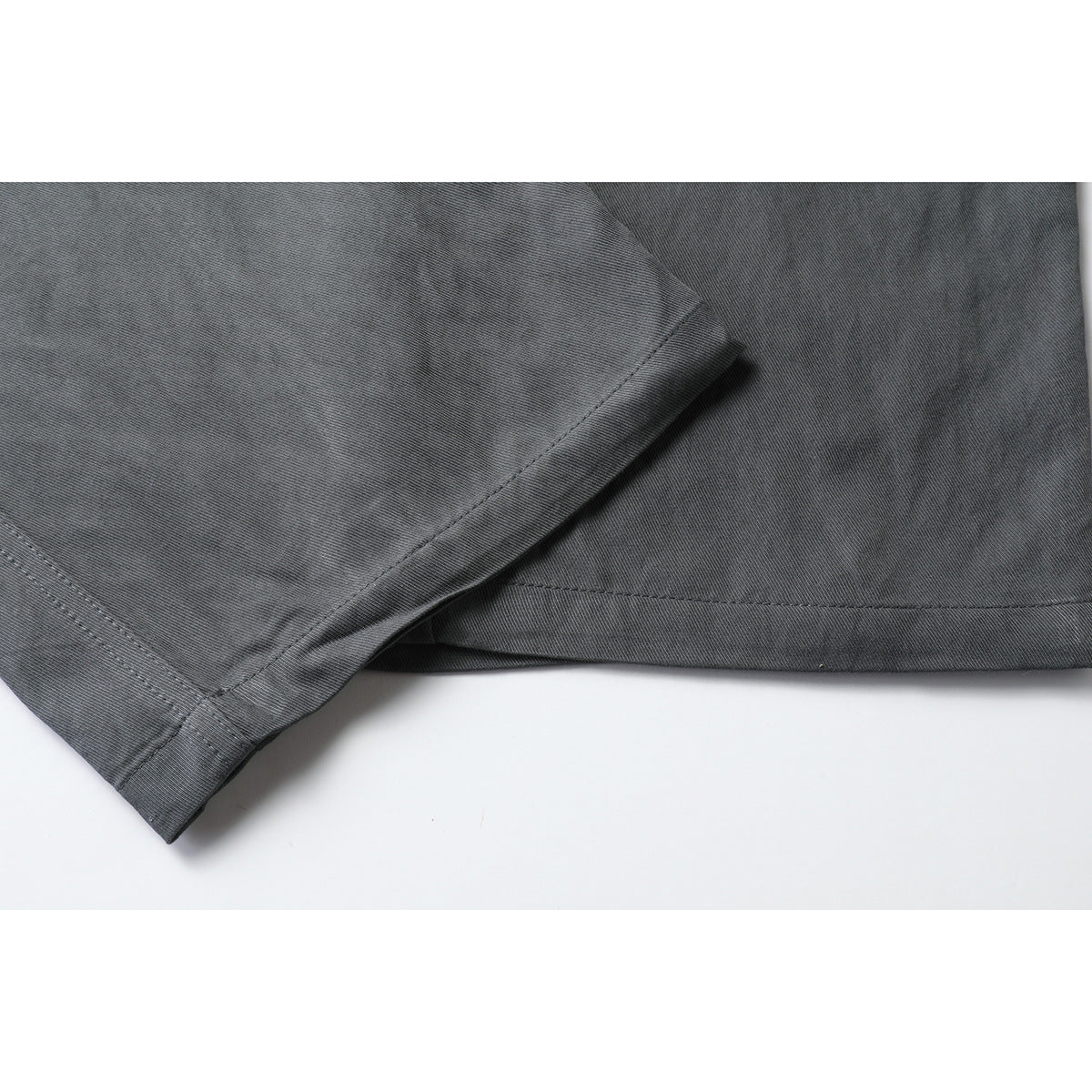 Close-up of charcoal gray trouser legs showing the stitched hems and fabric texture.