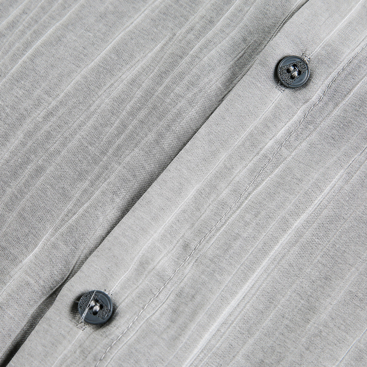 Close-up of gray striped shirt fabric, a button, and the stitched front placket.