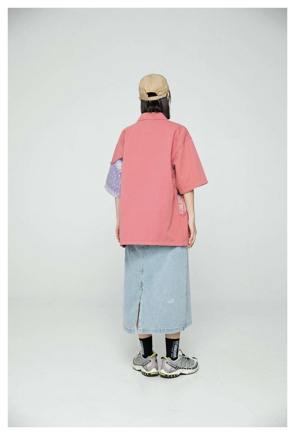 Back view of a model wearing an oversized coral shirt, with patchwork panels visible at the sides.