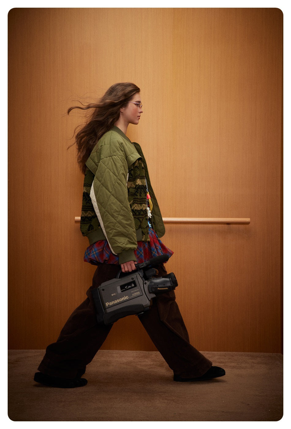 Side view of a model wearing an olive and cream bomber jacket with patterned fleece sections.