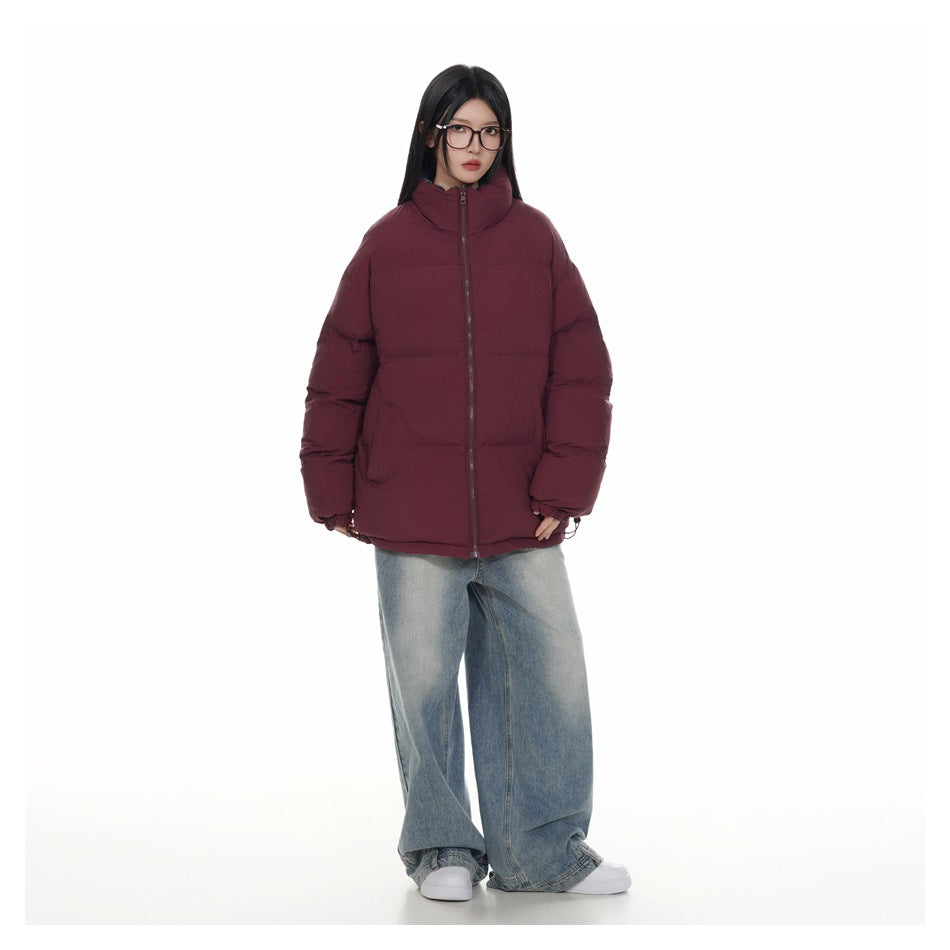Model wearing a zipped burgundy puffer jacket with wide-leg light-wash jeans and white sneakers, full-length front view