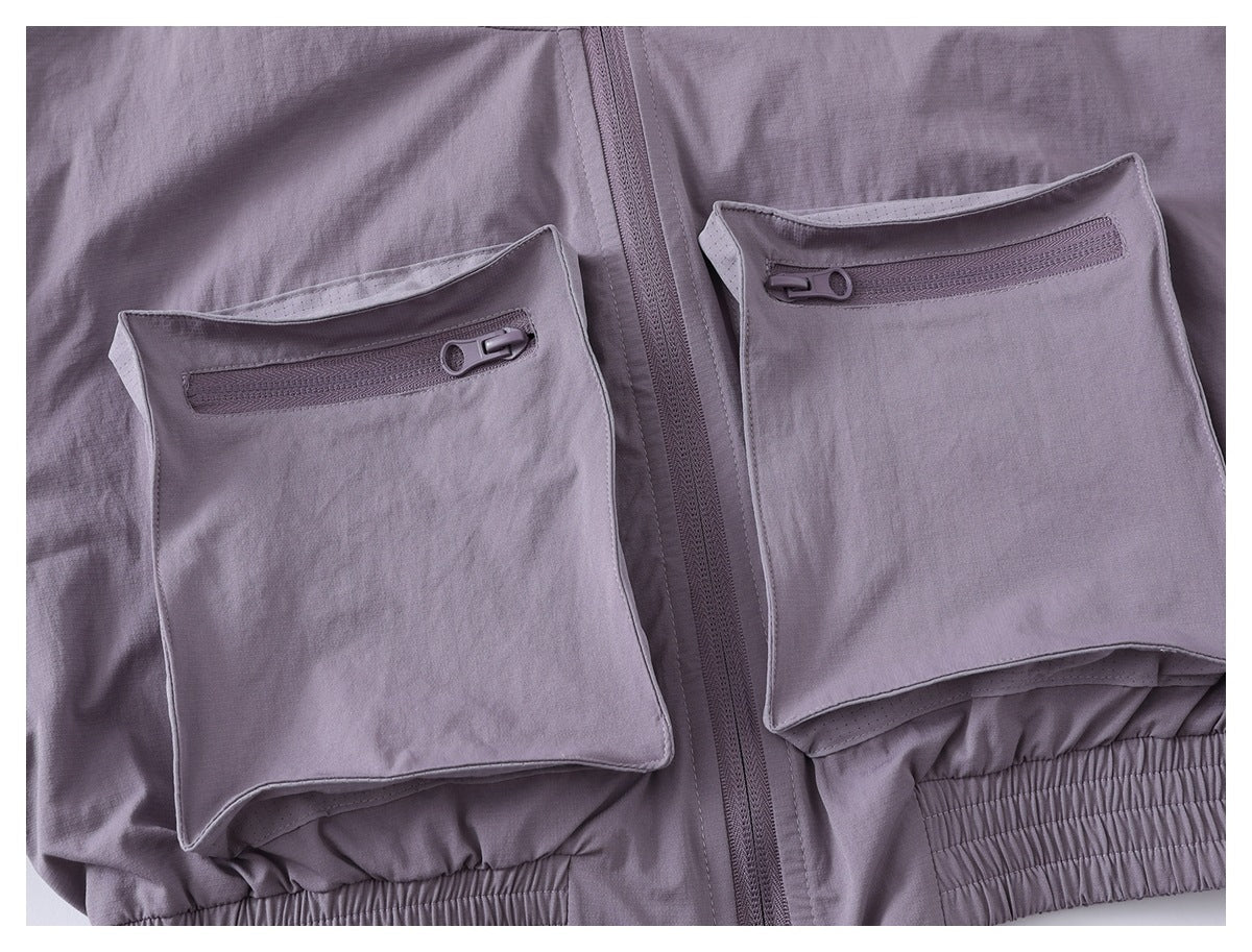 Close-up of two large zippered front pockets on a lavender jacket, with the center zipper and gathered hem visible.
