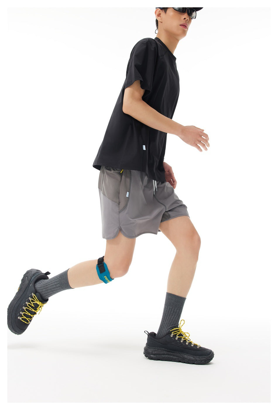 Side view of a model running in loose gray shorts with a drawstring waist and curved hems.