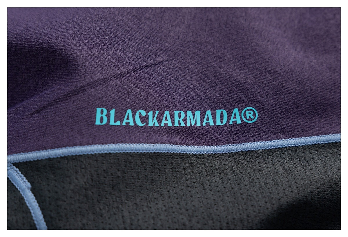 Close-up of dark purple and black fabric with pale blue piping and a turquoise BLACKARMADA logo.