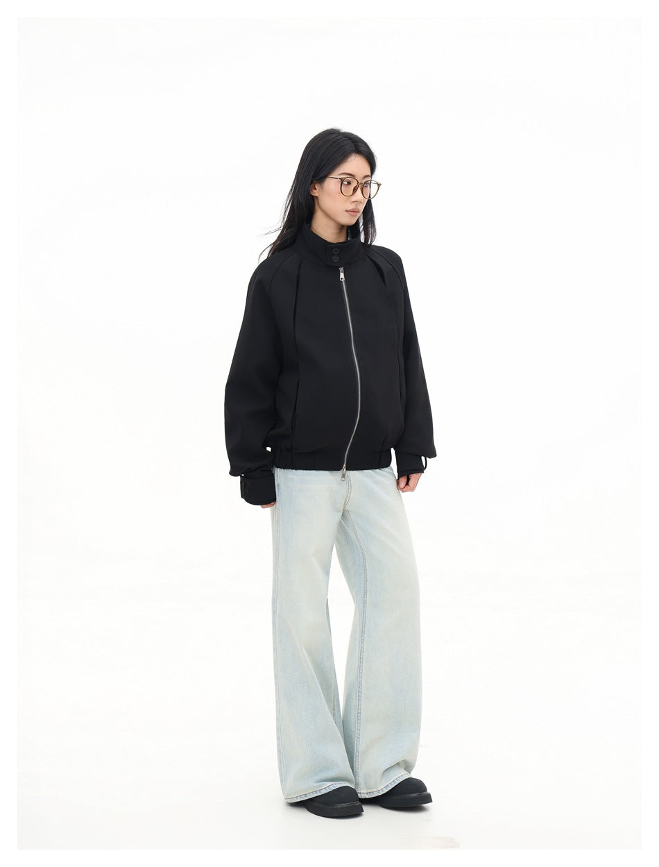 Model in a black zip-front jacket with a high button collar and pale wide-leg jeans, shown at an angle.