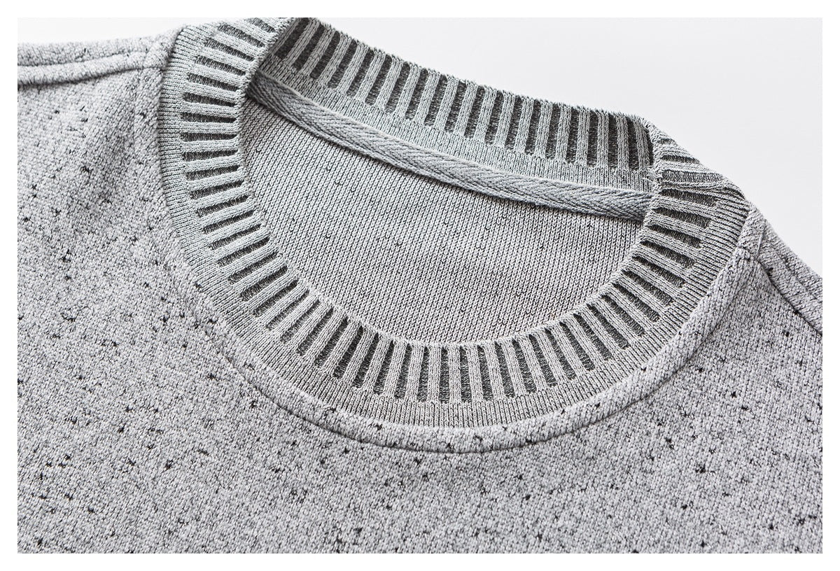 Close-up of a gray flecked knit sweater’s round neckline with ribbing and dark vertical accents.