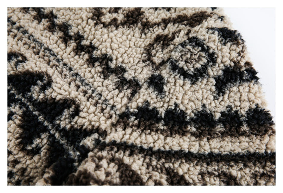 Close-up showing the thick, curly pile and irregular black and brown pattern on beige fleece.