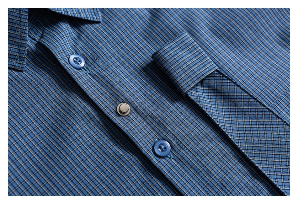Close-up of a blue plaid shirt's button placket and cuff with blue buttons.