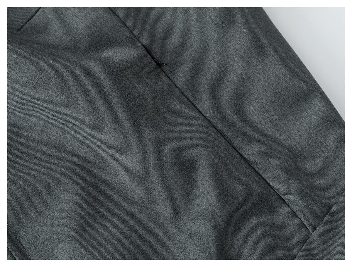 Close-up of a dark gray garment panel with a diagonal seam and a small black zipper pull.