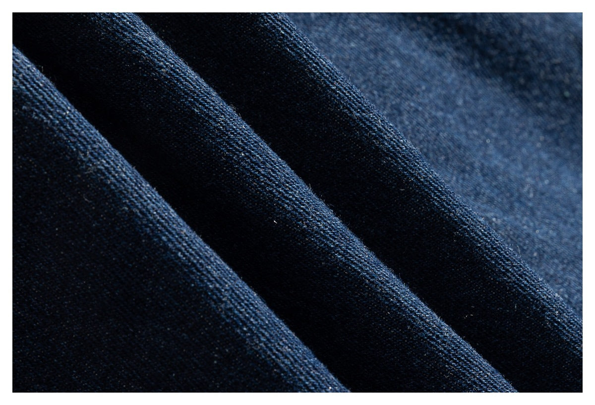 Macro view of dark blue denim fabric folded to show its woven texture.