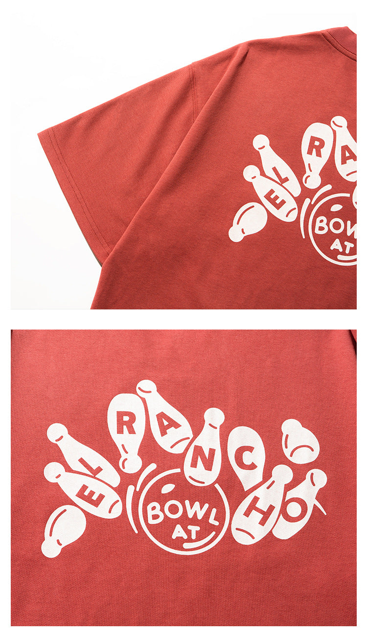 Close-up of a rust-red T-shirt with a large white bowling-pin graphic and lettering.