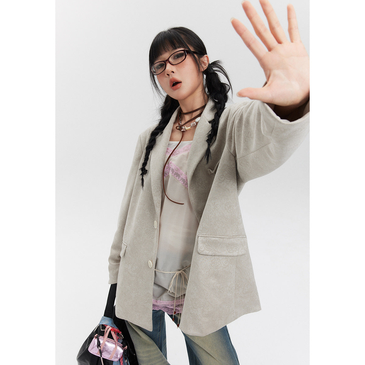 Model wearing a light beige patterned blazer over a white camisole and jeans.