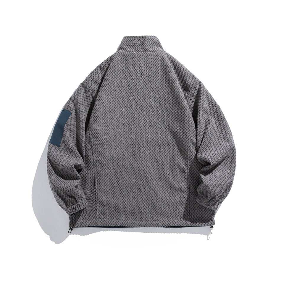 Back view of a gray patterned jacket with a high collar, elastic cuffs, hem toggles, and a blue sleeve patch.