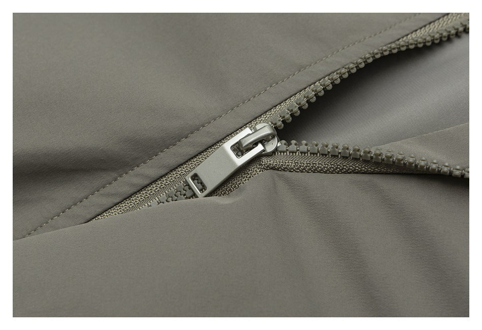 Macro view of a metal zipper on olive-gray fabric.