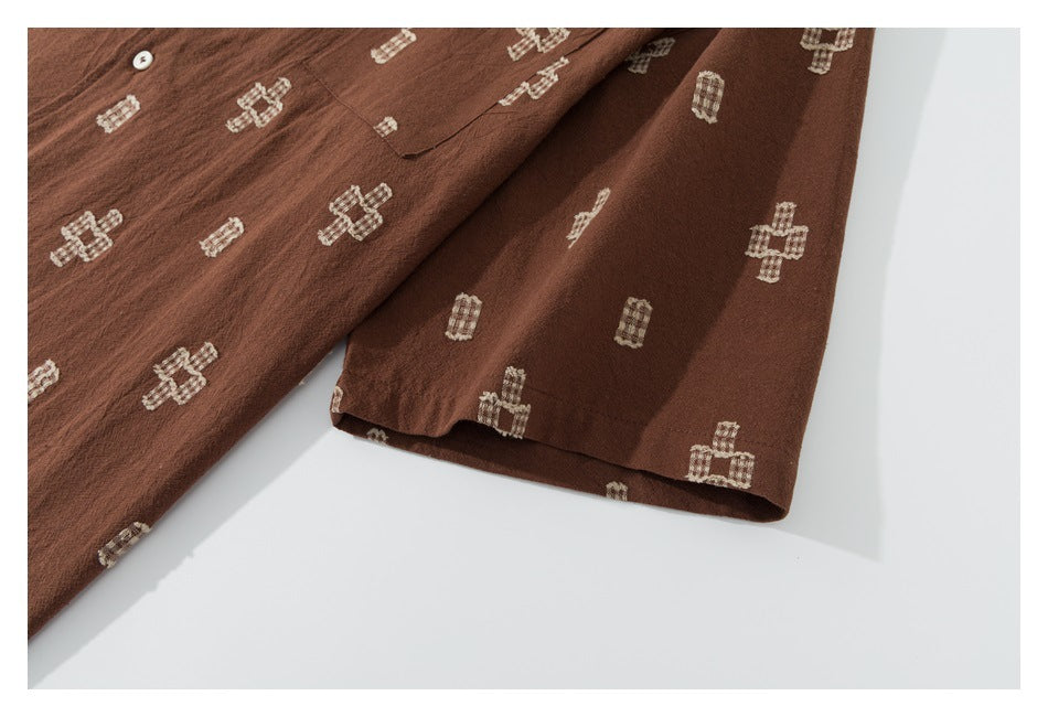 Close-up of a brown garment's sleeve and hem with scattered cream geometric motifs.