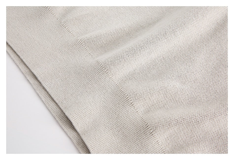 Close-up of the cream sweater's ribbed hem and fine textured knit.