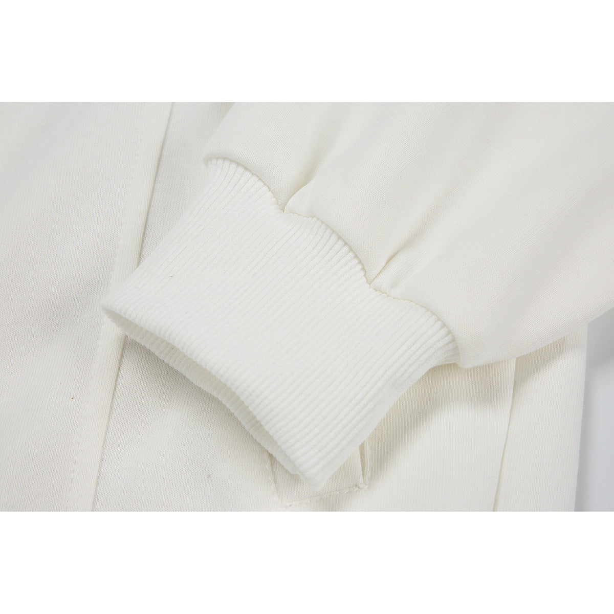 Close-up of a white sleeve with a wide ribbed cuff against the garment body.