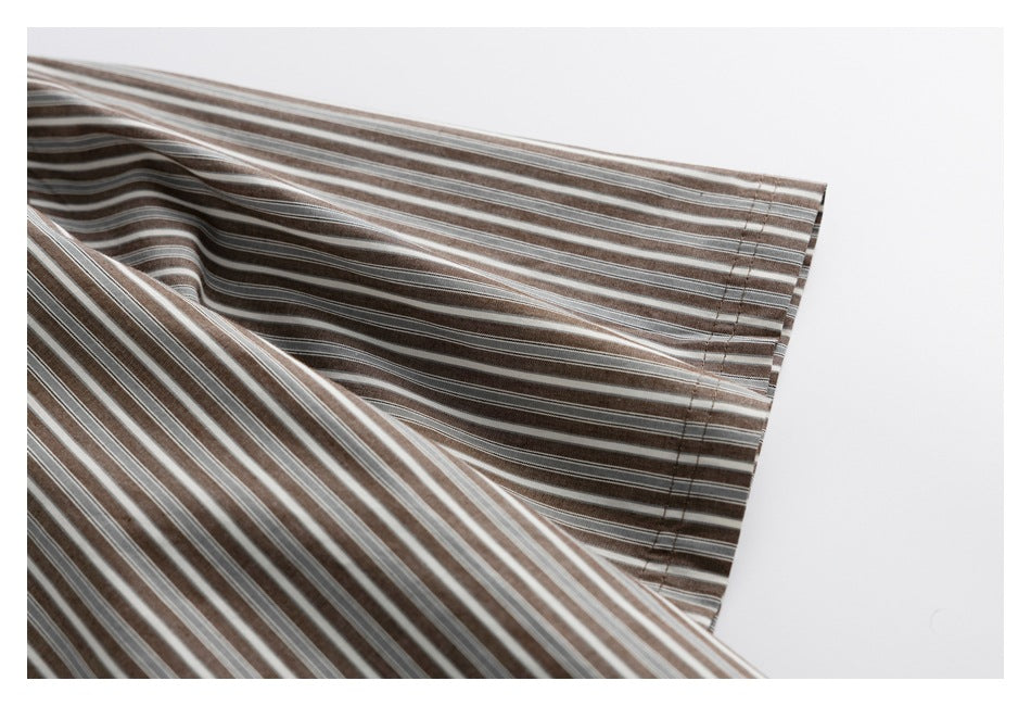Close-up of a brown, gray, and white striped shirt sleeve and stitched cuff.