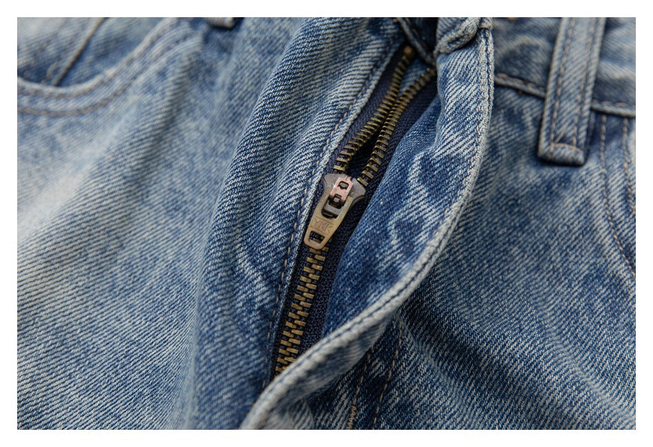 Close-up of the partly open zipper fly and waistband of light-wash blue jeans.