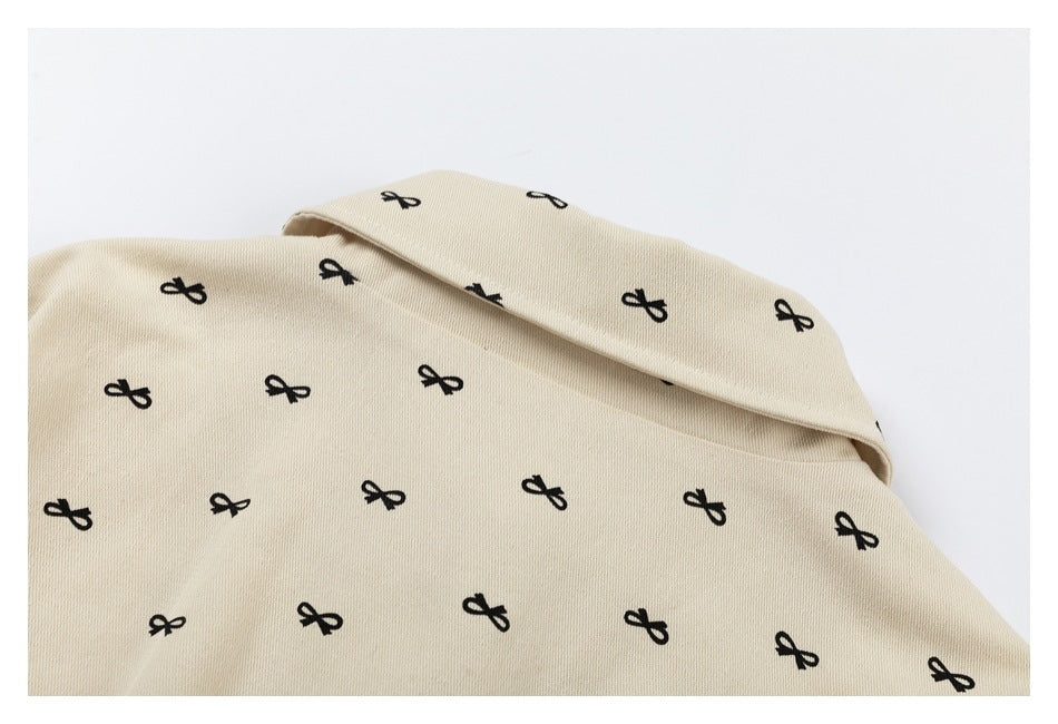 Close-up of the wide collar and upper back of a beige garment printed with small black bows.