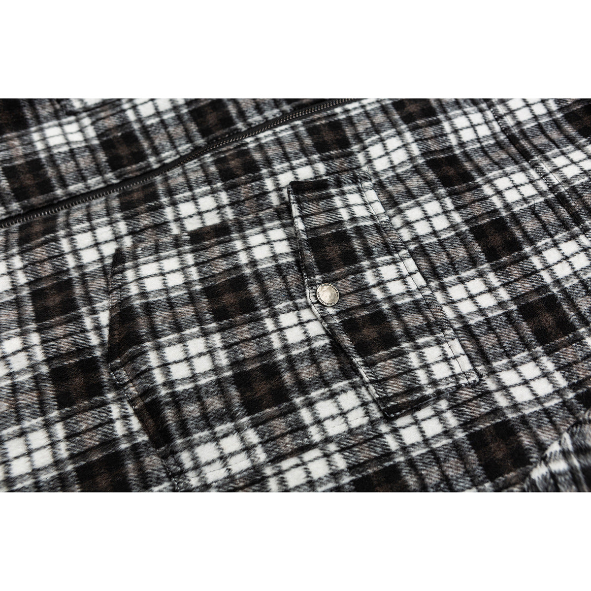Close-up of the black-and-white plaid jacket front, zipper, and buttoned flap pocket.
