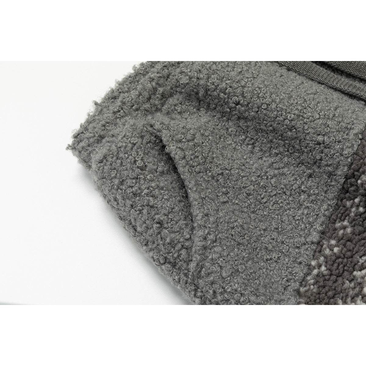 Close-up of a seam or pocket area on gray loop-textured fabric, with a dark drawstring visible at the top.
