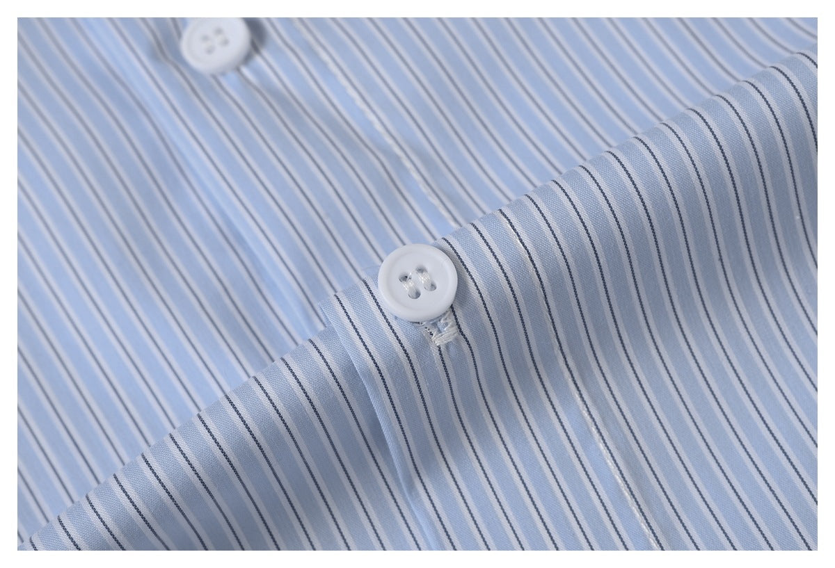 Close-up of light blue fabric with narrow dark and white stripes and a white button.